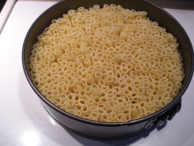 The cooked noodles stacked in the spring-form pan.